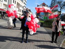 Poseł Patryk Jaki rozdaje biało - czerwone balony, które po chwili zostały wypuszczone do nieba.